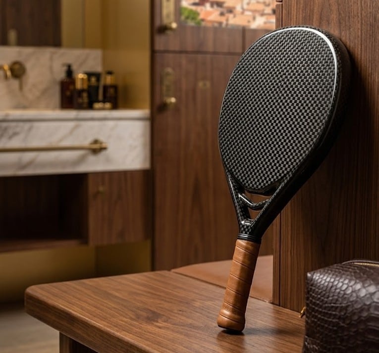 Carbon-weave AUREA padel racket with leather grip in a luxury interior